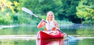 Woman driving with kayak on forest river